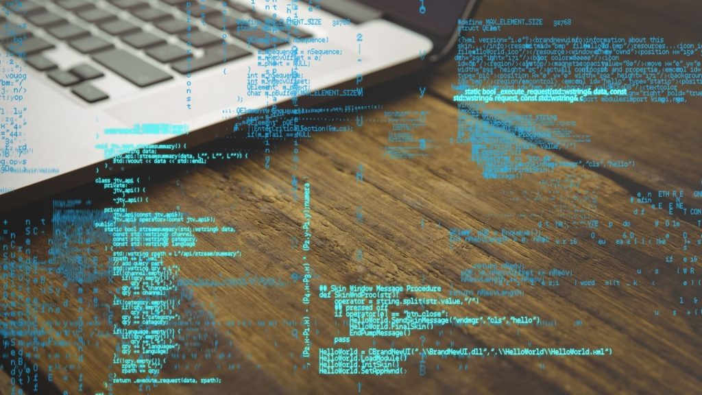 Código sobre fondo de portátil simboliza la protección digital de Hawke Transit System frente a ciberataques y fraudes por correo electrónico.